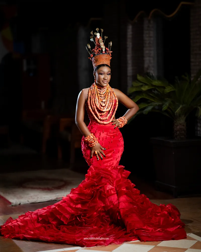 Coral-crowned bride, hand on hip, palm plant in background
