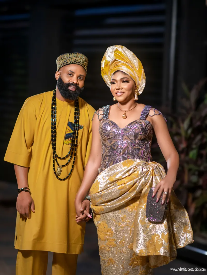 Couple portrait in matching mustard-gold traditional attire, holding hands
